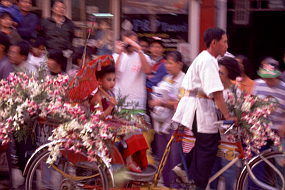 後ろに座席の着いた3輪自転車が、目一杯にめかし込んだ女の子を乗せて通り過ぎる。