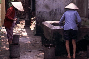 大きなバケツを持ってきた女が、共同の井戸で水を汲む。やはりノンをかぶっている。