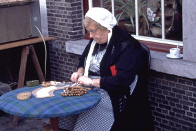 通りに出したテーブルで手芸品を作るおばあちゃん。