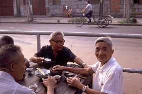 露天の店で朝食を済ませ、茶を楽しむ老人たち。