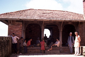 村を見下ろす王宮跡の建物、日陰でのんびり過ごす人々。